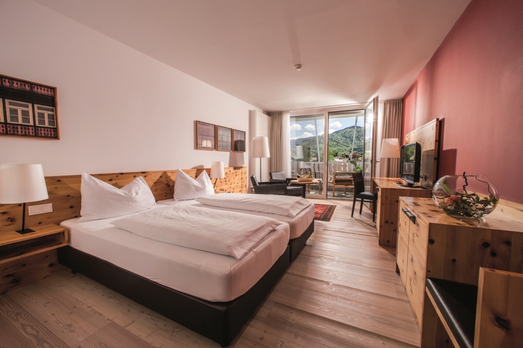 Hotelzimmer mit Bett, Sofaecke, Komoden und Blick auf den Balkon